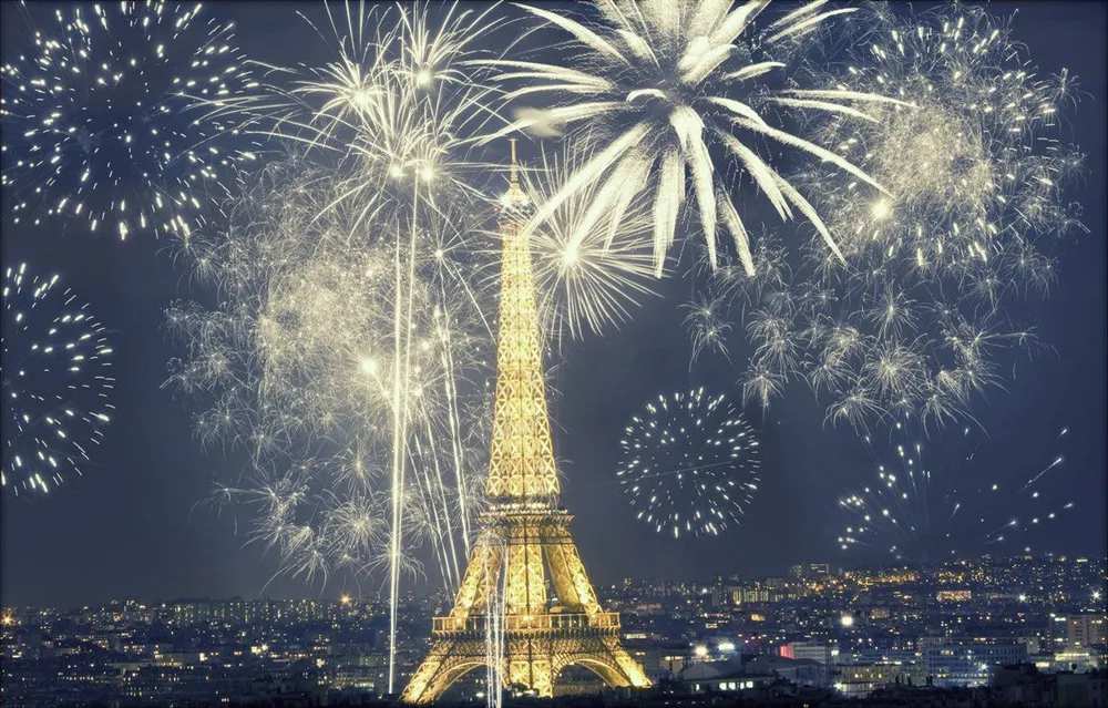 Fuegos artificiales junto a la Torre Eiffel al atardecer en la víspera de Año Nuevo.