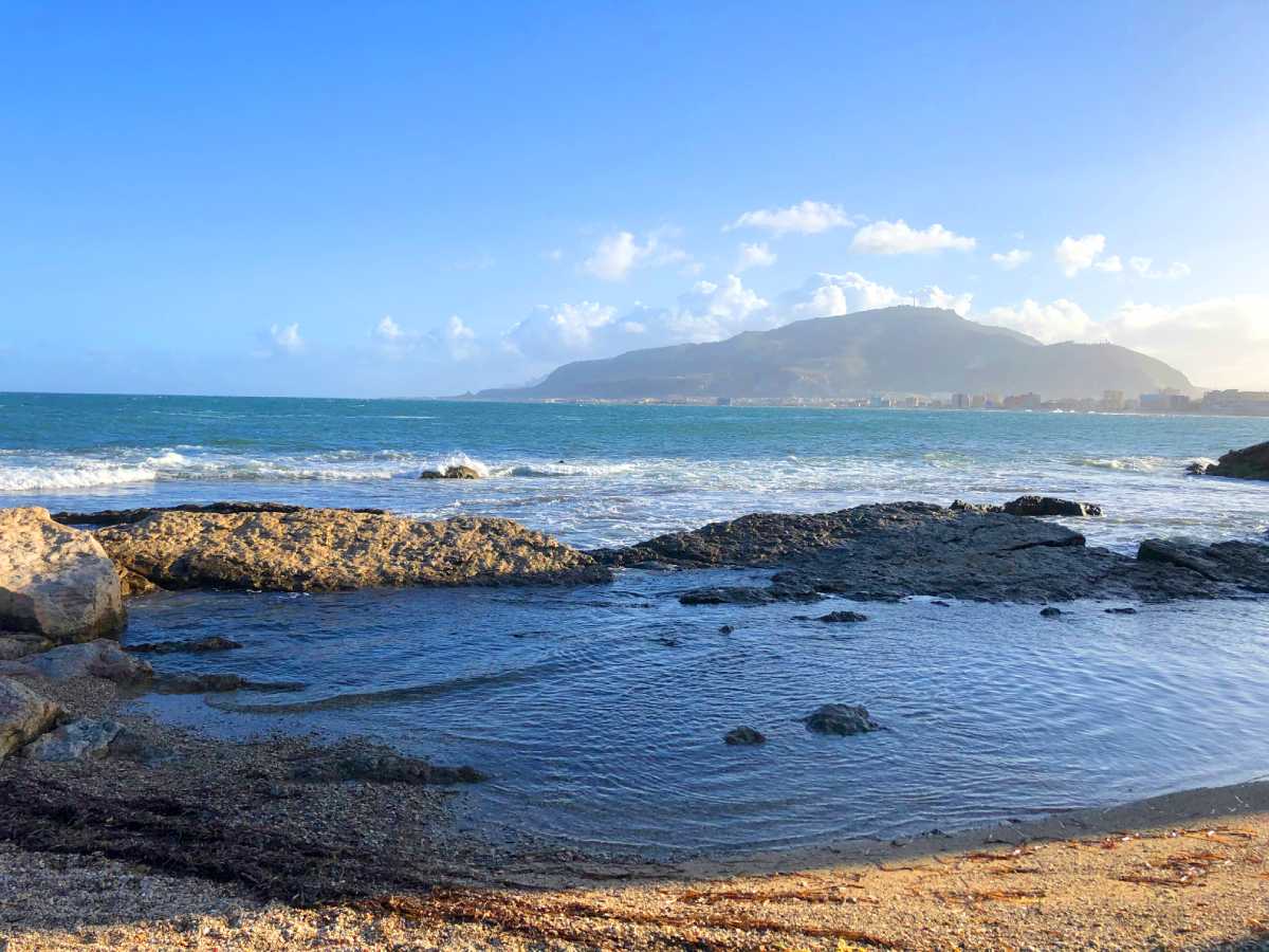 Vista del mar desde la costa de Trapani, Sicilia, con el monte Erice al fondo bajo cielo azul claro