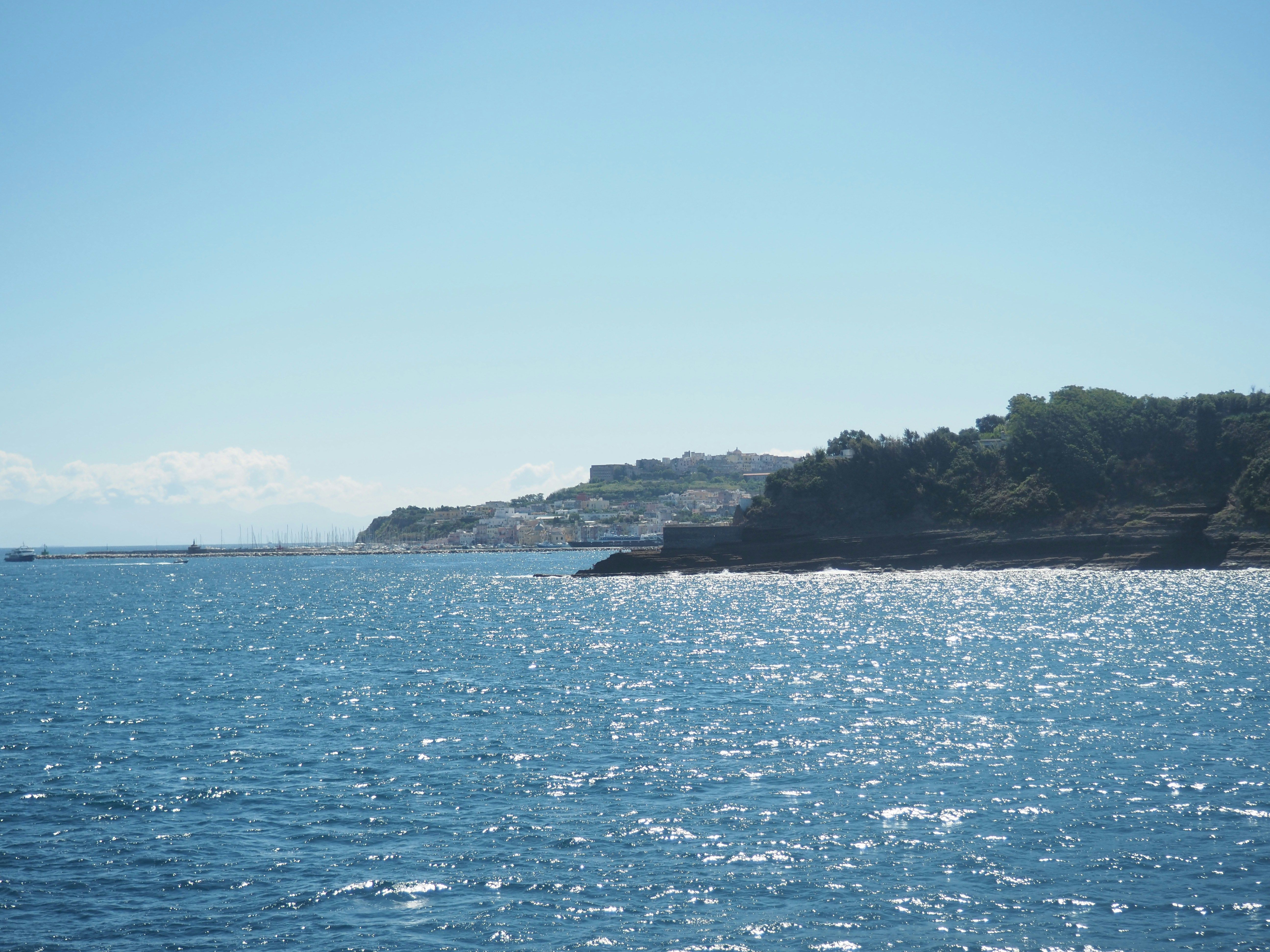 sea glistening in the sun with the town of Ischia in the background