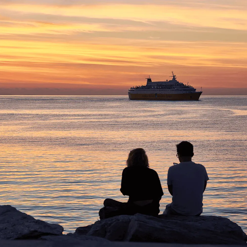 two people watching a ferry at sunset