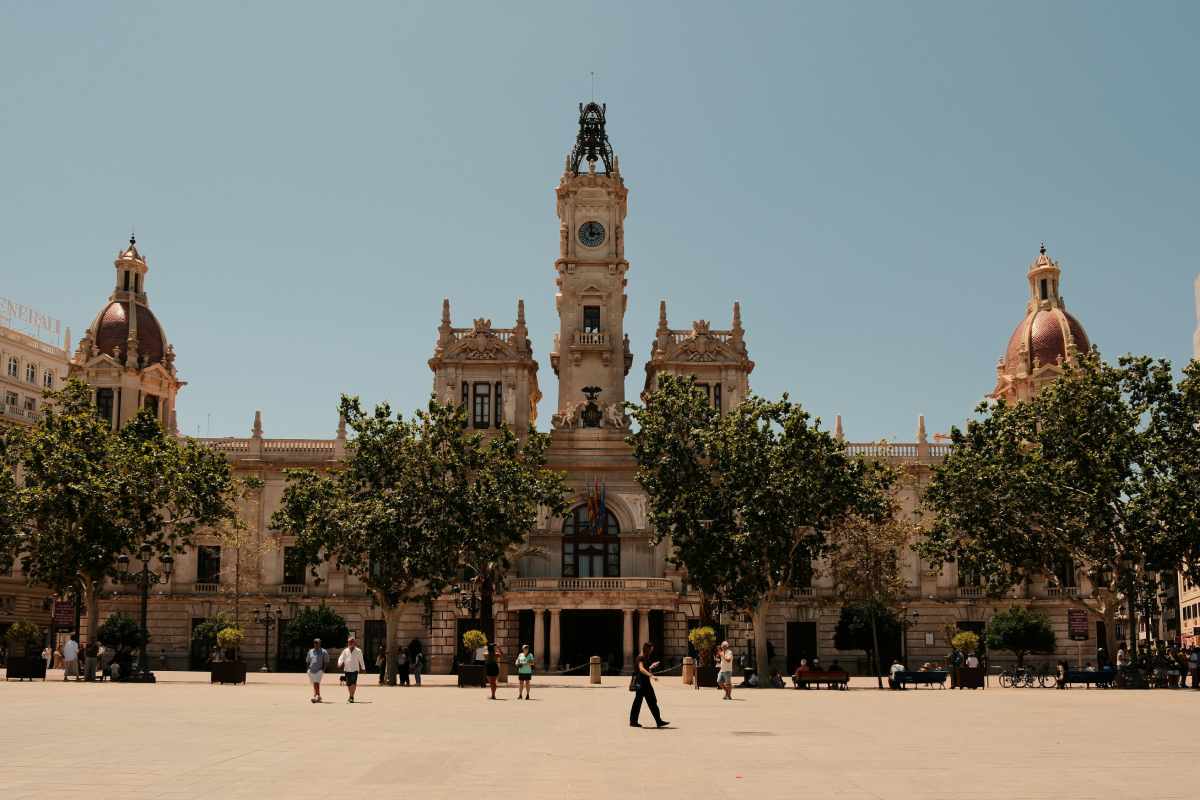 Place avec arbres et edifice beige avec horloge au dessus