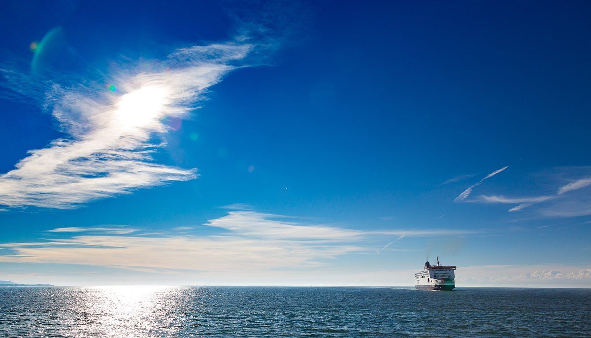 veerboot die op zee vaart terwijl de zon op het water schittert