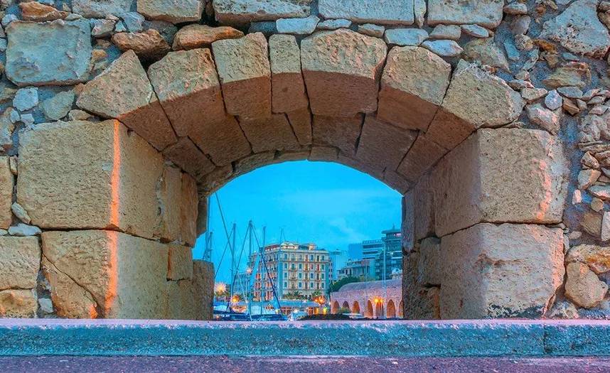 Vista del puerto de Heraclión a través de un arco de piedra de las antiguas murallas venecianas.