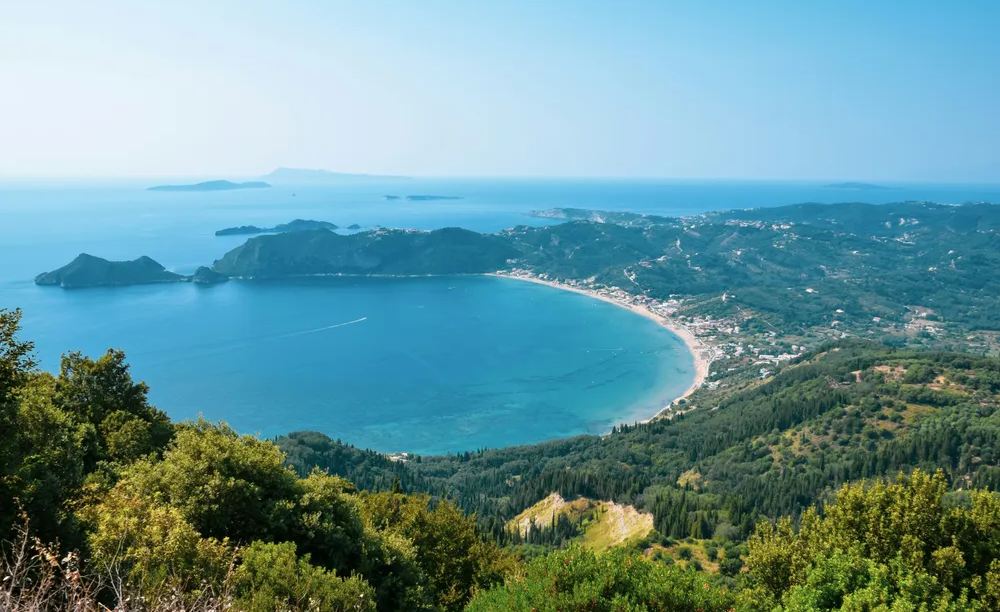 Panorámica de la costa de Corfú con colinas verdes y aguas turquesas